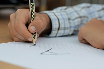 Close-up of hand writing with pencil on paper