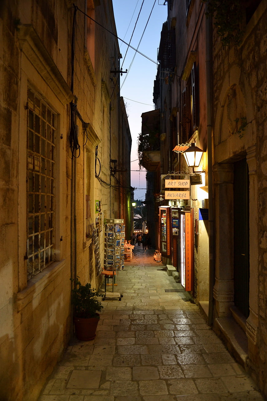 Narrow cobblestone alley in old town at dusk with warm street lights