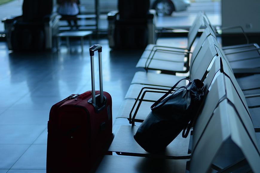 Red Suitcase and Black Bag on Airport Terminal Seating