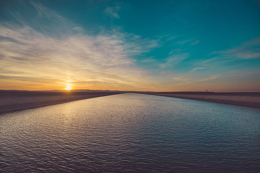 Sunset over a wide irrigation canal with golden sky