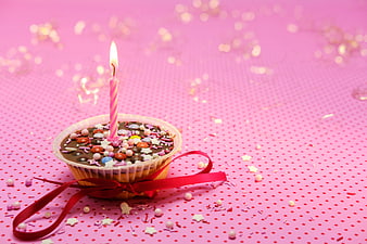 Birthday Muffin With Candle And Red Ribbon On Pink Background