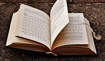 Open hymnal book with sheet music on stone surface