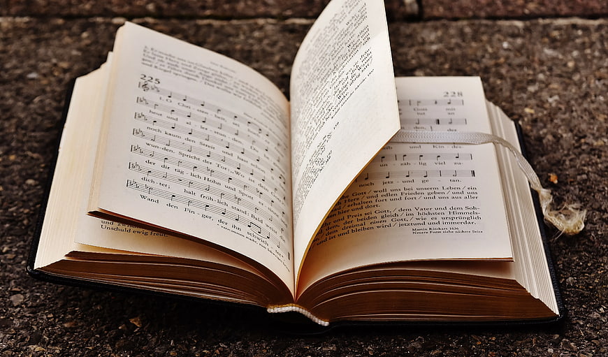 Open hymnal book with sheet music on stone surface