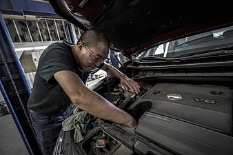 Automotive Mechanic Inspecting Car Engine In Repair Shop