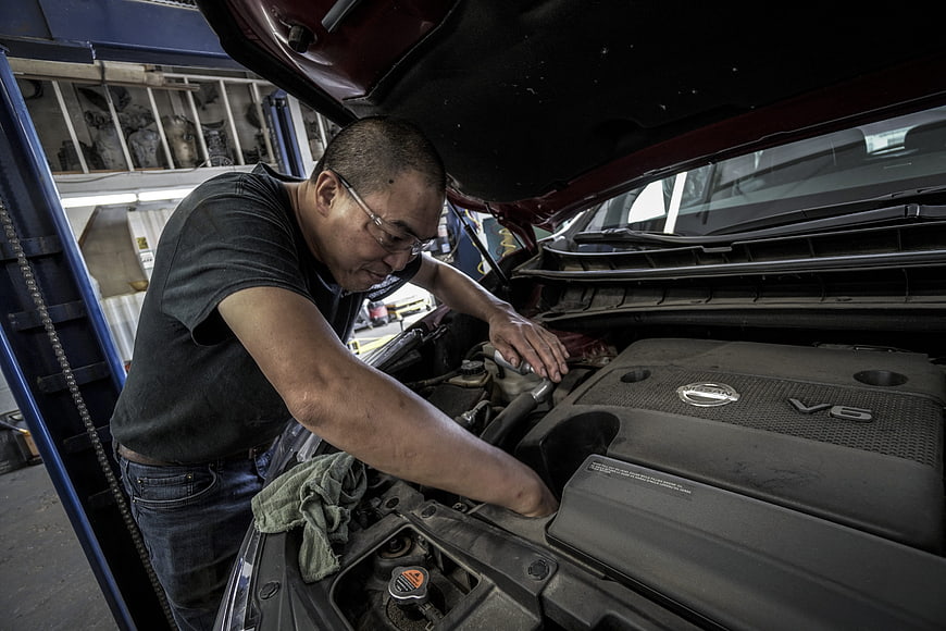 Automotive Mechanic Inspecting Car Engine In Repair Shop