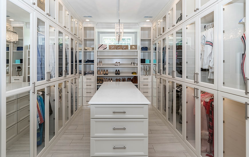 Luxurious White Walk-In Closet With Central Island And Glass Cabinets