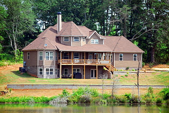 Large Two-Story Brown House With Balcony Near Pond