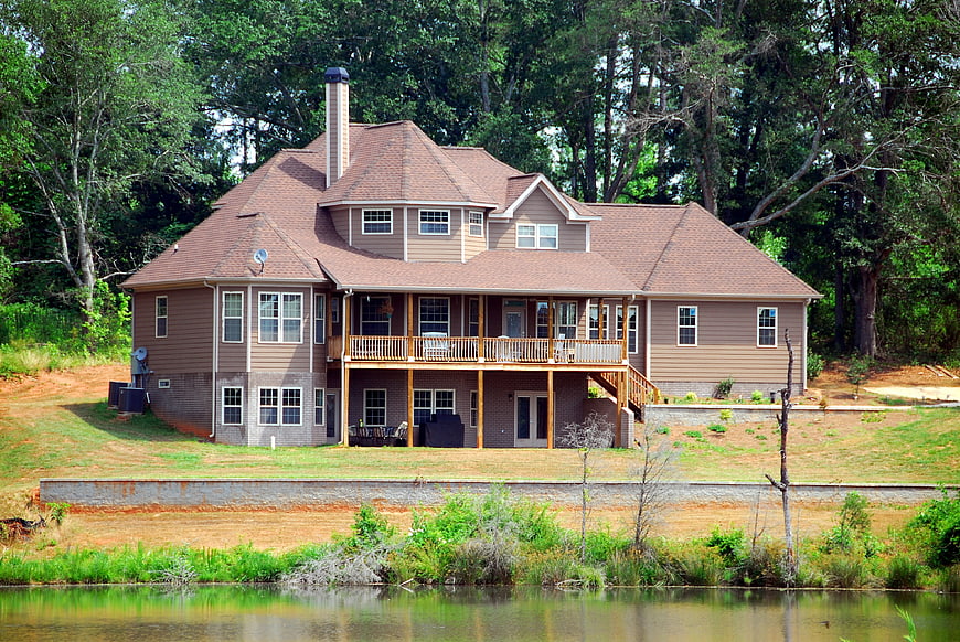Large Two-Story Brown House With Balcony Near Pond