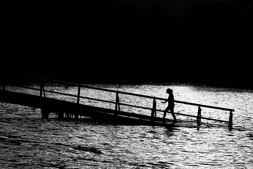 Silhouette of person walking on pier at night
