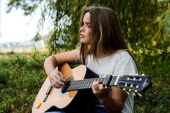 Young Woman Playing Acoustic Guitar Outdoors in Nature