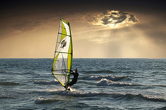 Windsurfer Gliding on Ocean Waves at Sunset