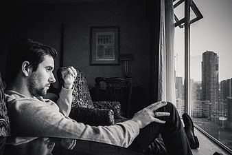 Contemplative man sitting by window looking at city skyline