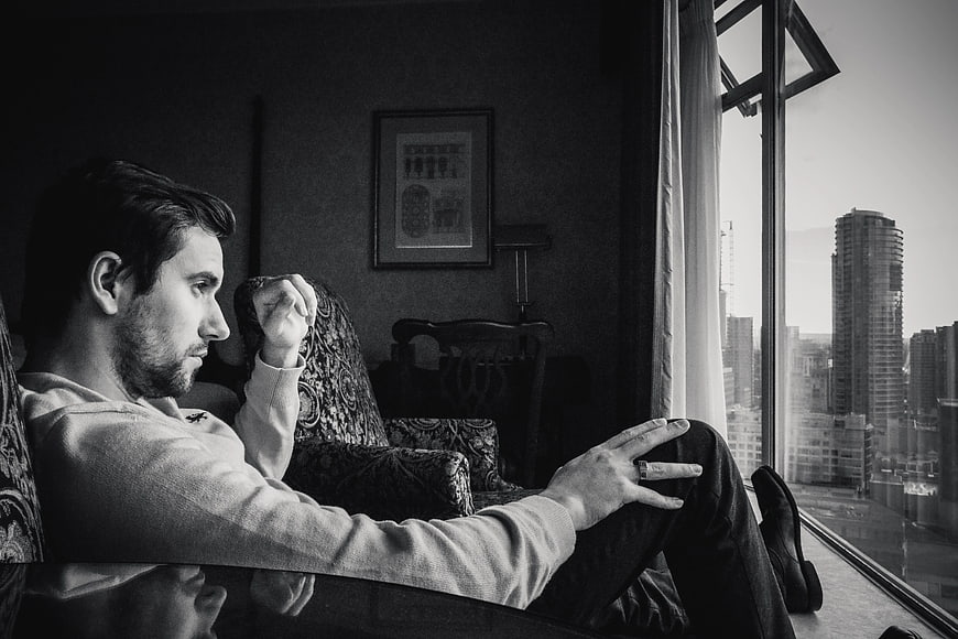 Contemplative man sitting by window looking at city skyline
