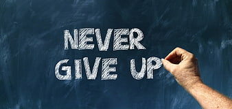 Hand writing never give up on a dark blue chalkboard with white chalk