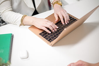 Woman Typing on Gold Laptop in Modern Office Workspace