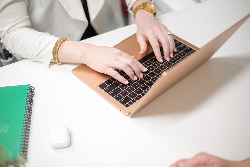 Woman Typing on Gold Laptop in Modern Office Workspace