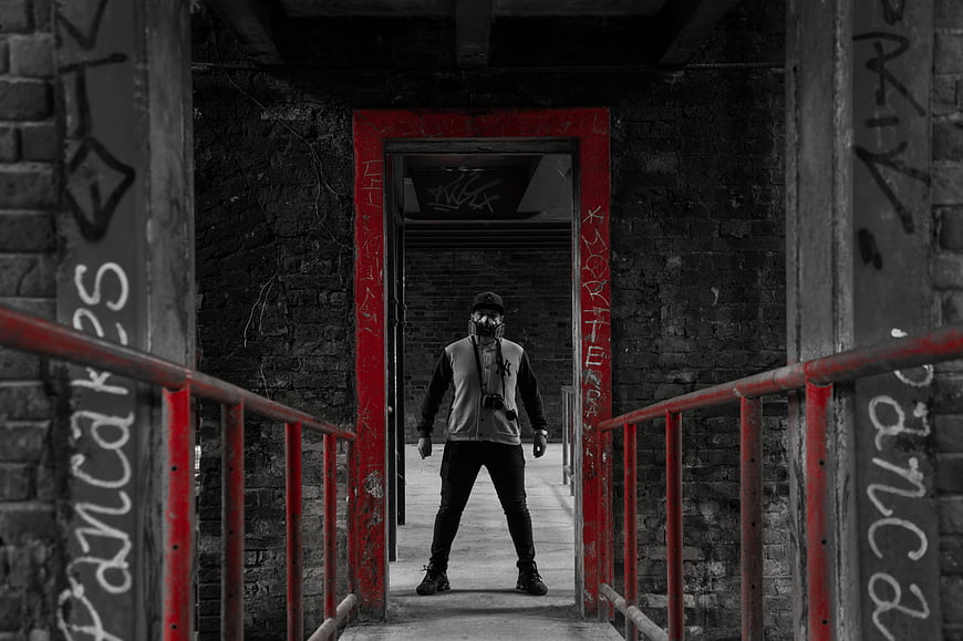 Man in Gas Mask Standing in Red Doorway of Abandoned Building