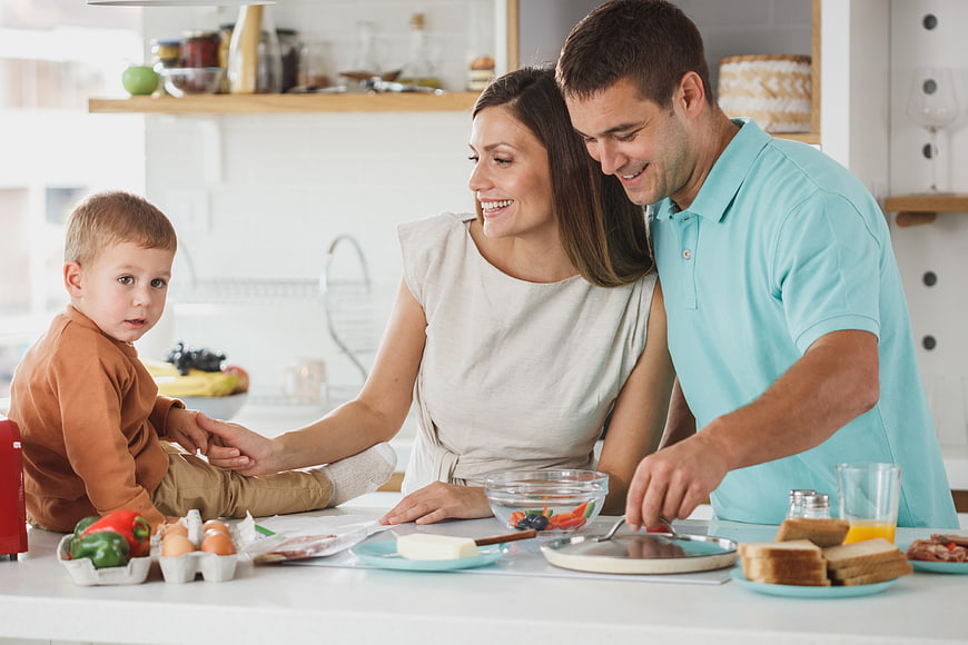 Happy family preparing breakfast together in modern kitchen