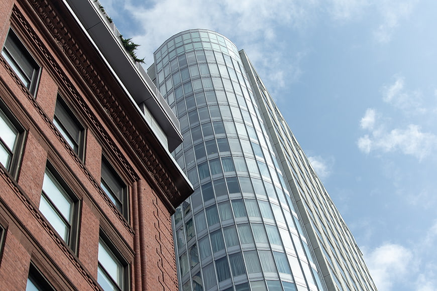Low angle view of modern glass skyscraper and historic brick building