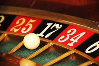 Close-up of roulette wheel with white ball on green felt