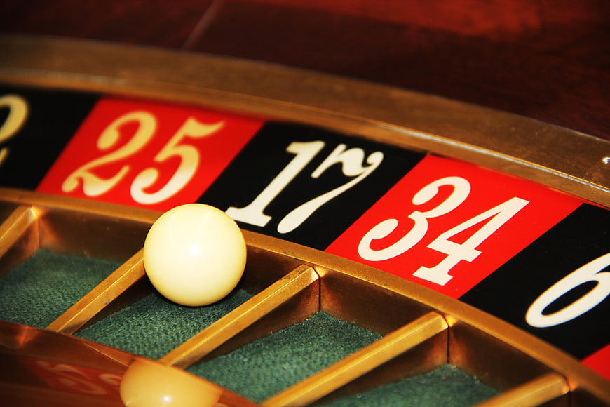 Close-up of roulette wheel with white ball on green felt