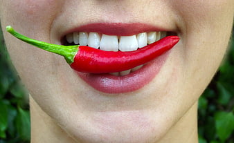 Close-up of woman holding red chili pepper in mouth