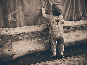 Toddler in denim overalls touching star curtain