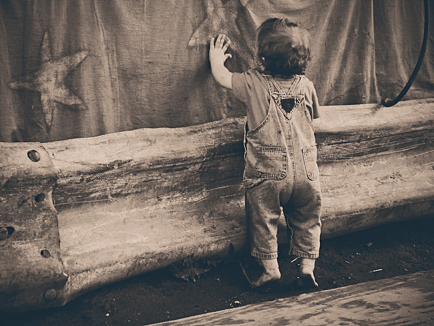 Toddler in denim overalls touching star curtain