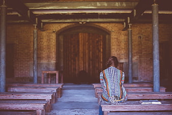 Woman Praying Alone in Old Brick Chapel Interior