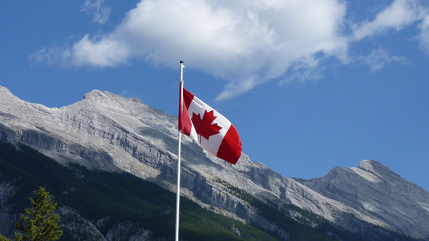 Canadian Flag Waving Against Rocky Mountain Landscape