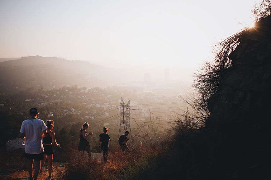 Group of Hikers on Trail Overlooking Hazy City at Sunset