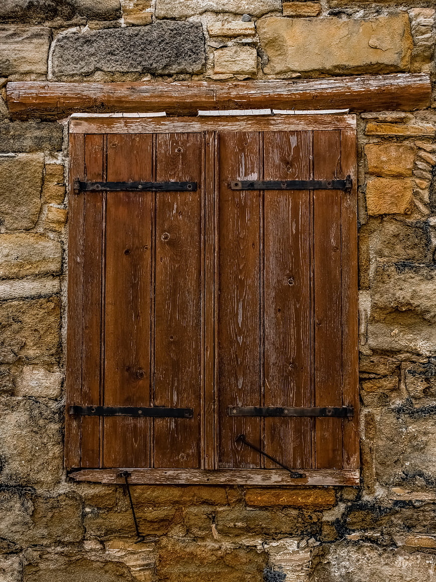 Weathered wooden shutters on rustic stone wall