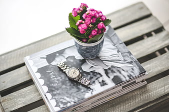 Silver watch and pink flowers on magazine stack
