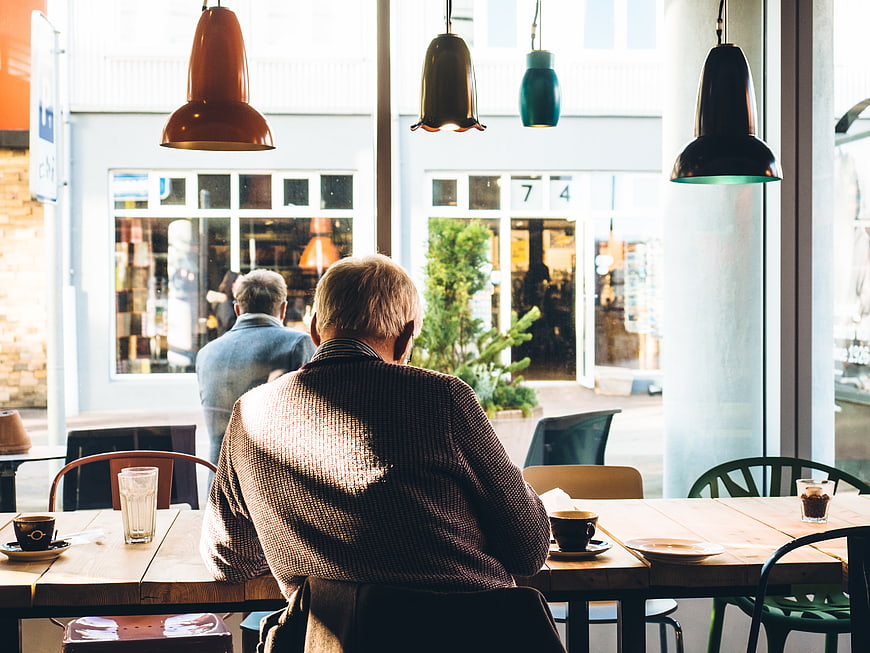 Senior man sitting at cafe table with coffee