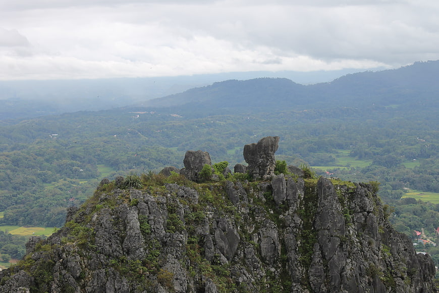 Rugged limestone karst peak overlooking lush green valley