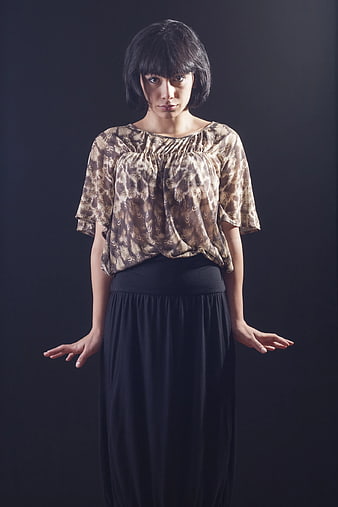 Woman with Bob Haircut and Patterned Blouse Against Dark Background