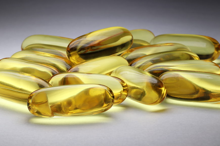 Golden Softgel Capsules on Gray Background