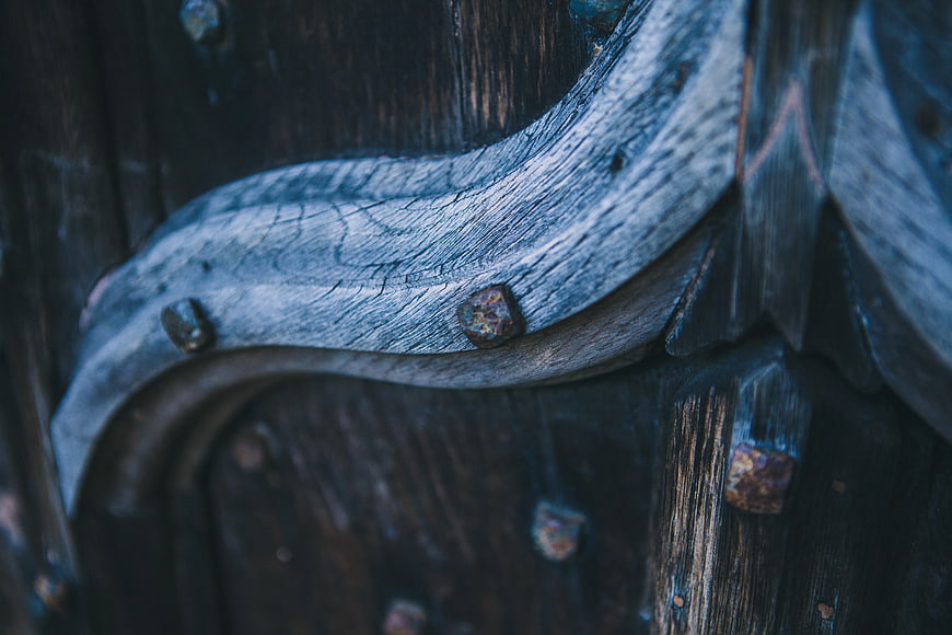 Close-up of weathered carved wood with rusty nails