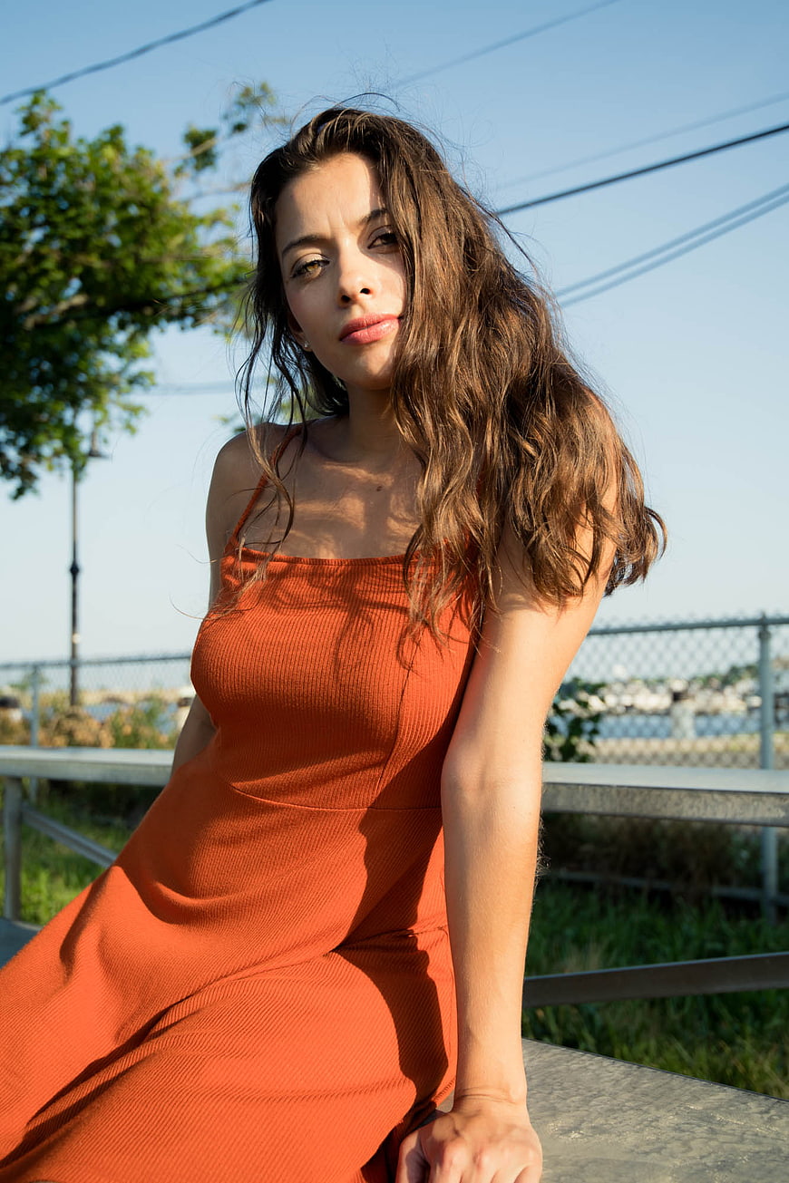 Brunette Woman in Orange Dress Sitting Outdoors