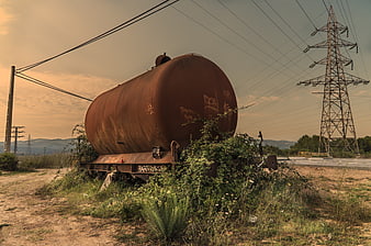 Rusty abandoned train tanker car in overgrown field