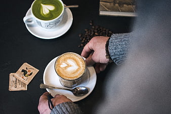 Overhead view of matcha and flat white coffee with hands