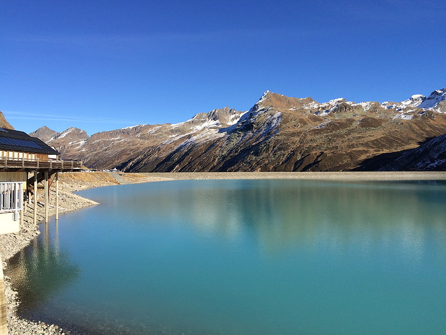 Turquoise alpine lake with snow-capped mountains and wooden building