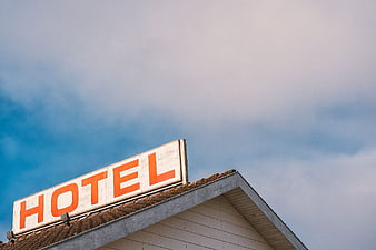 Retro Orange Hotel Sign on Roof Against Blue Sky