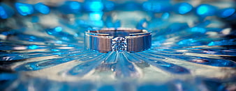 Silver diamond ring on blue textured glass background