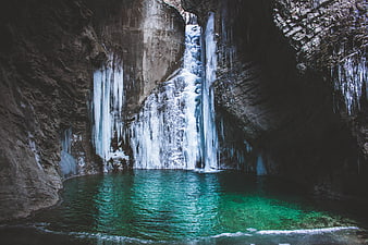 Frozen waterfall in cave with turquoise pool