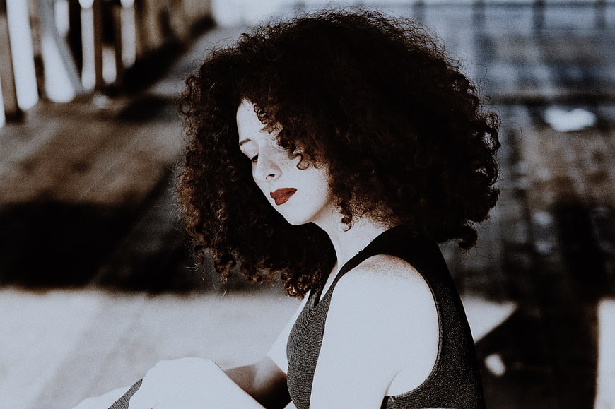 Woman with curly hair looking down in moody portrait