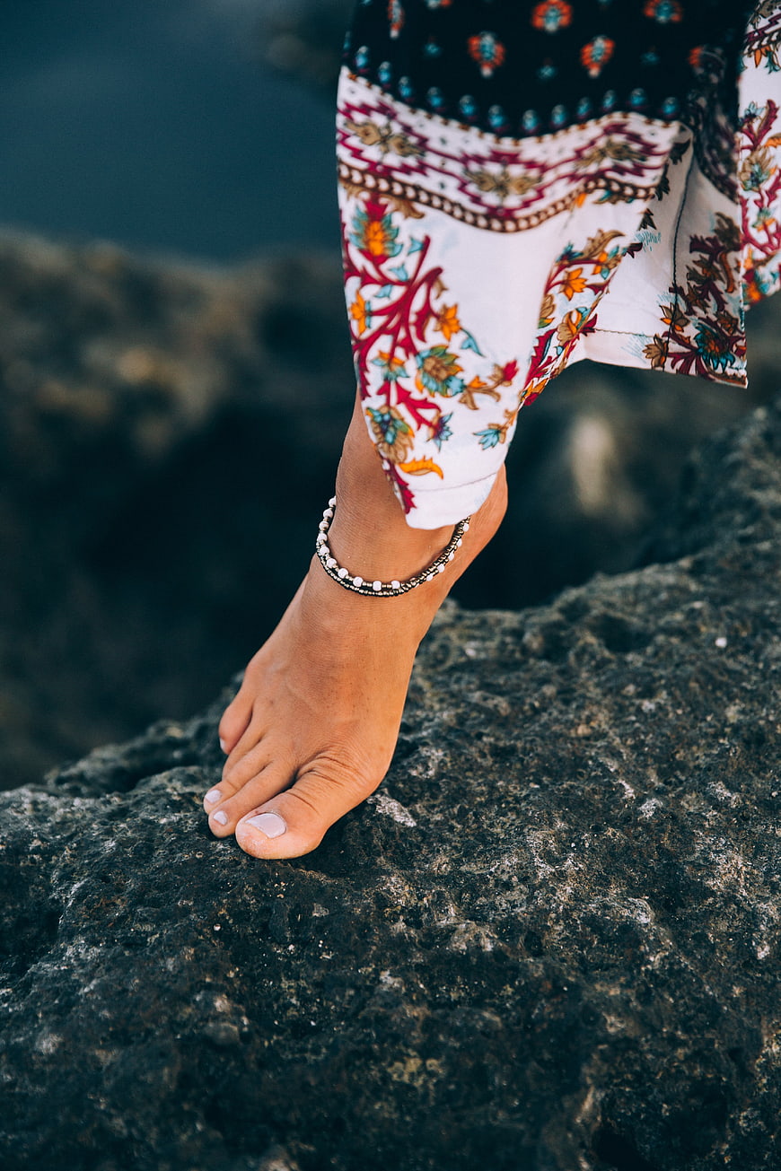 Barefoot woman wearing boho anklet on rocky shore