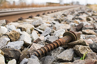 Rusty railway screw on gravel ballast near train tracks