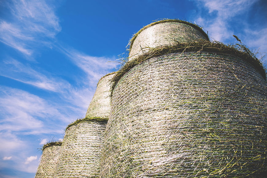 Stack of Round Hay Bales Against Blue Sky