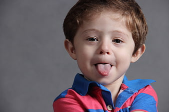 Playful Young Boy Sticking Out Tongue In Studio Portrait